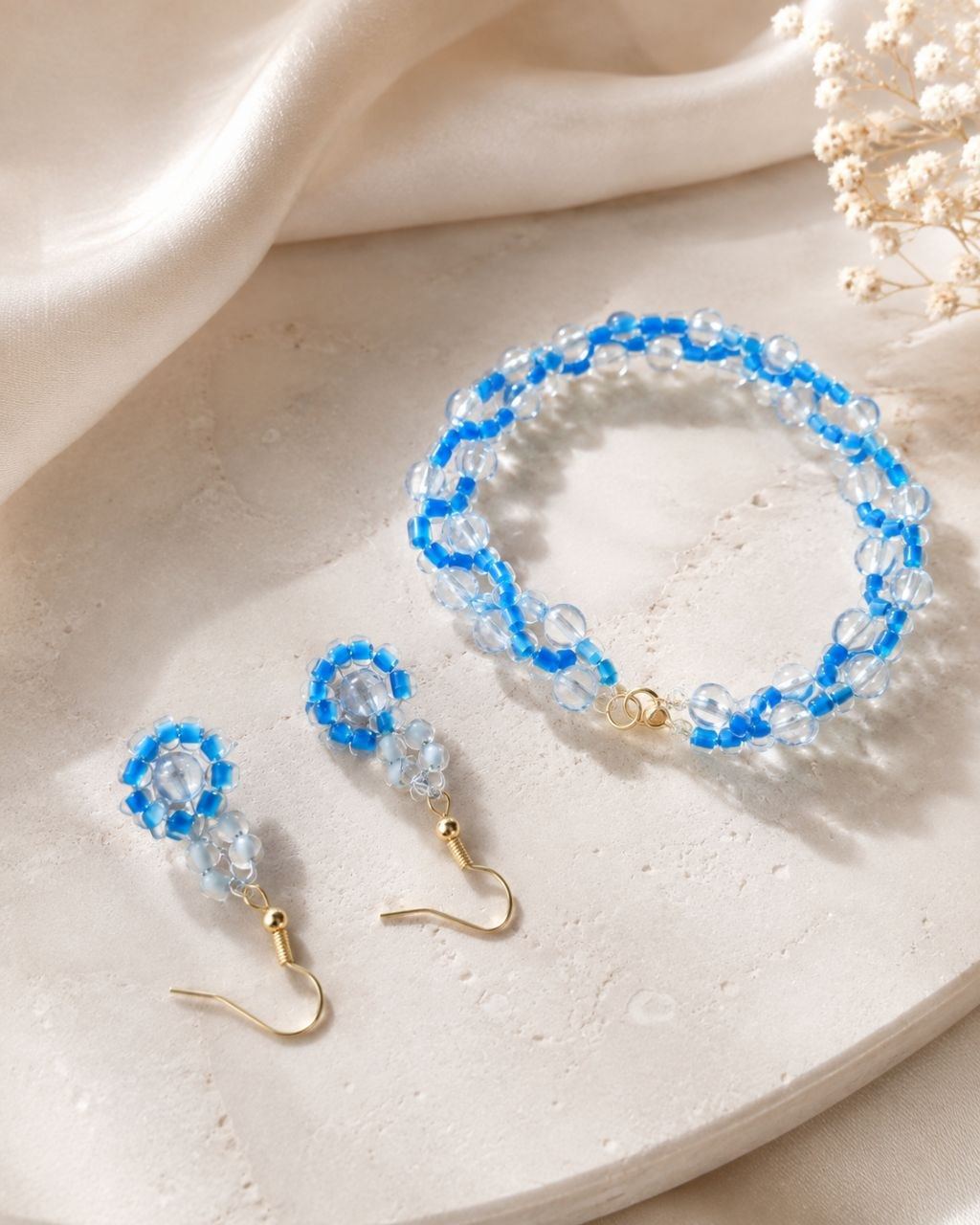 Azure bracelet and earrings laid out on marble